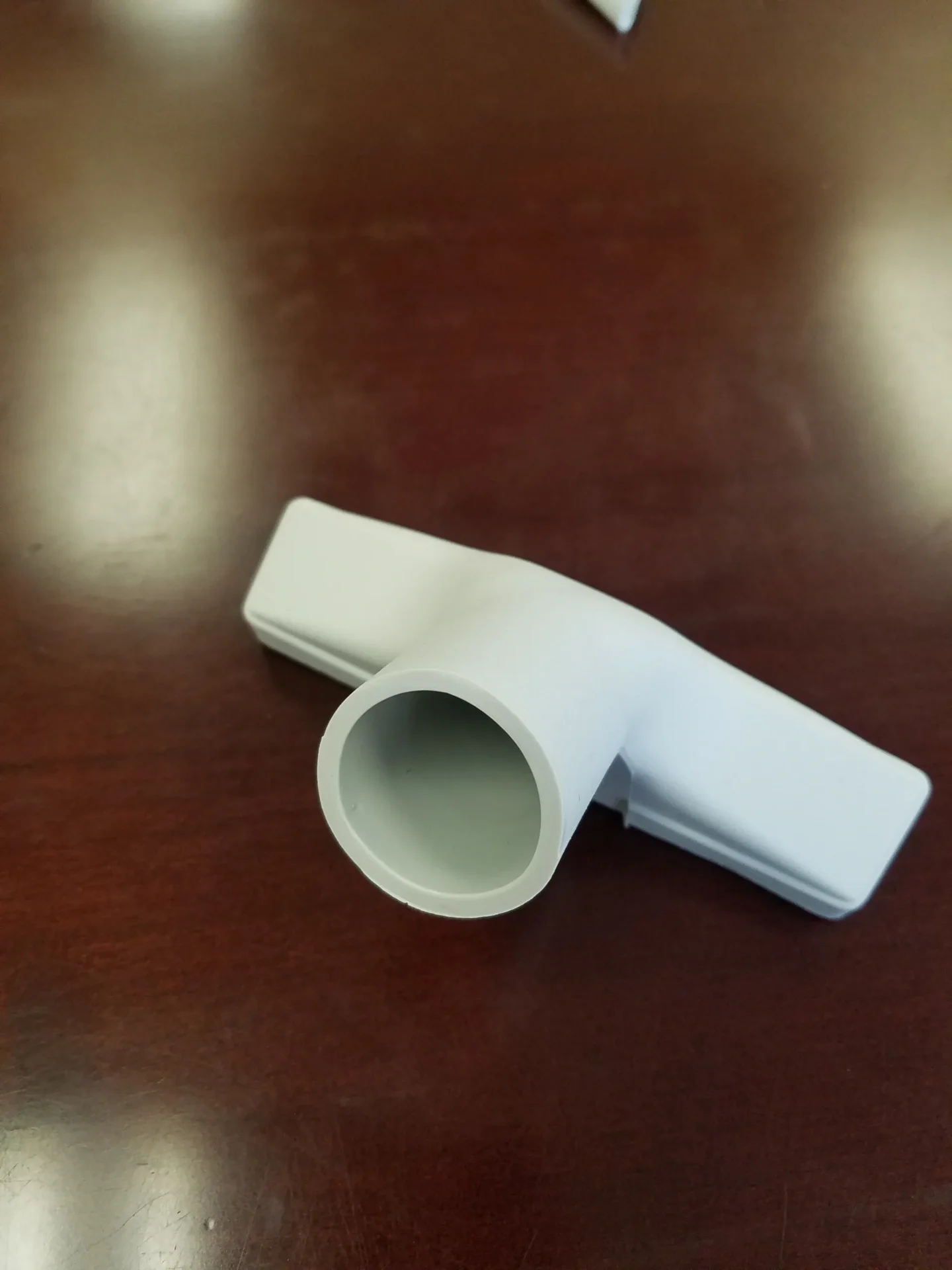 A white plastic pipe sitting on top of a wooden table.