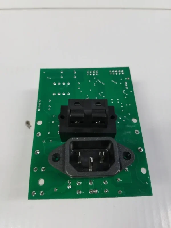 A green circuit board with an electrical outlet on it.
