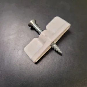 A white piece of plastic with a screw and one nail.