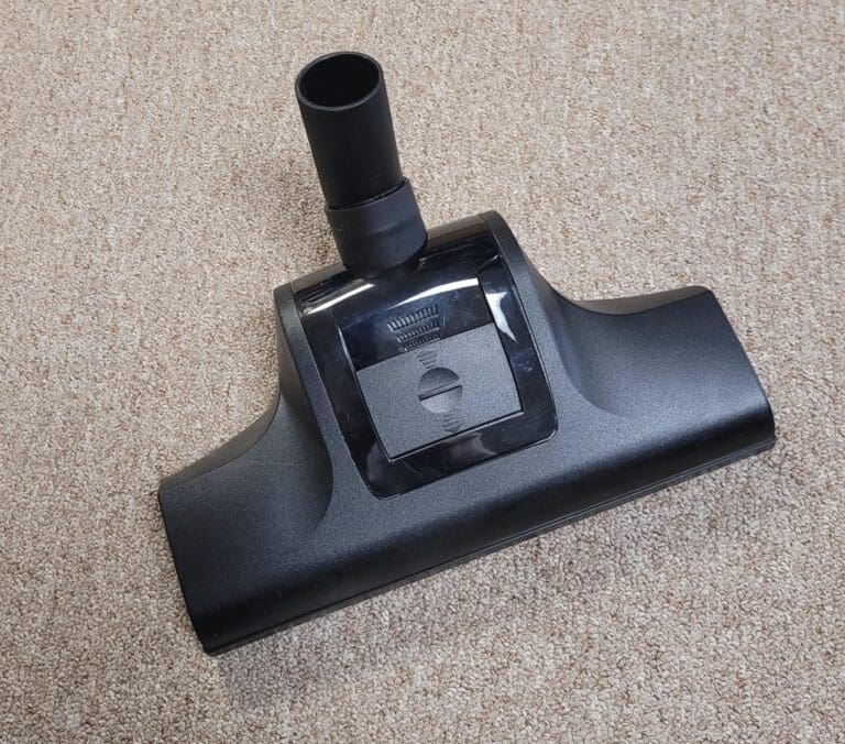 Vacuum cleaner attachment on carpet backdrop.